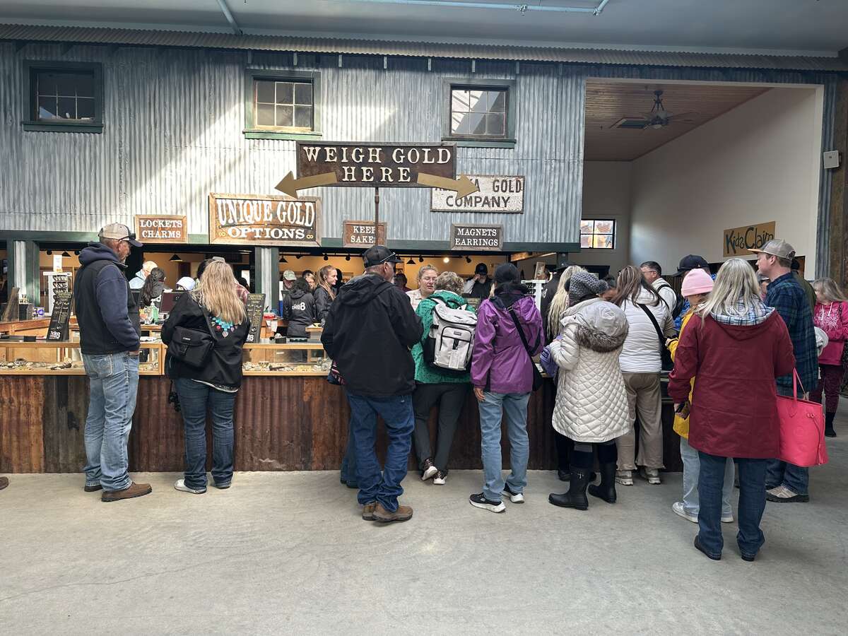 Visitors gathered inside Gold Dredge 8 in Fairbanks, Alaska, at the “Weigh Gold Here” station, where freshly panned gold is measured and turned into keepsakes like lockets, charms, and earrings.