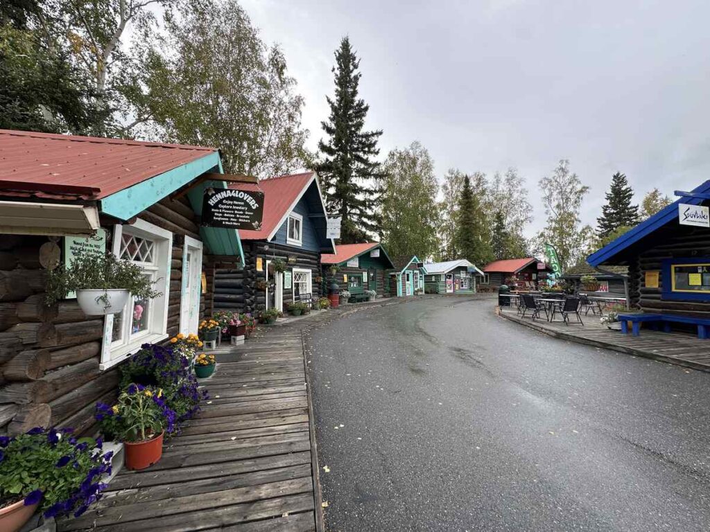 A row of historic log cabins with colourful painted trim, now housing shops and exhibits at Pioneer Park in Fairbanks, Alaska.
