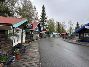 A row of historic log cabins with colourful painted trim, now housing shops and exhibits at Pioneer Park in Fairbanks, Alaska.