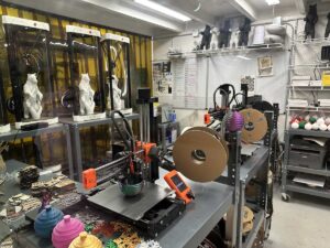 A workshop with 3D printers and laser cutters producing colourful ornaments and bear figurines for sale in the gift shop.