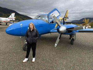 Traveller standing in front of a small blue twin-propeller plane used for Arctic Circle flight tours.