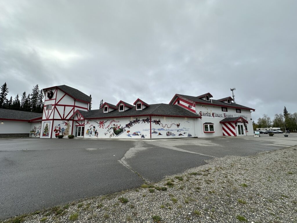 Exterior of the Santa Claus House in North Pole, Alaska, painted in red-and-white stripes with festive murals.