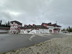 Exterior of the Santa Claus House in North Pole, Alaska, painted in red-and-white stripes with festive murals.
