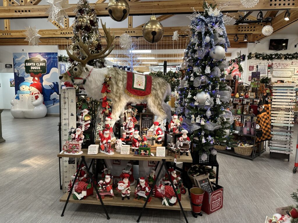 Christmas display inside the Santa Claus House featuring decorated trees, Santa figurines, and a life-sized reindeer statue.