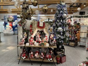 Christmas display inside the Santa Claus House featuring decorated trees, Santa figurines, and a life-sized reindeer statue.