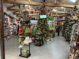 Festive Christmas store interior at the Santa Claus House in North Pole, Alaska, decorated with Grinch-themed merchandise and Christmas trees.