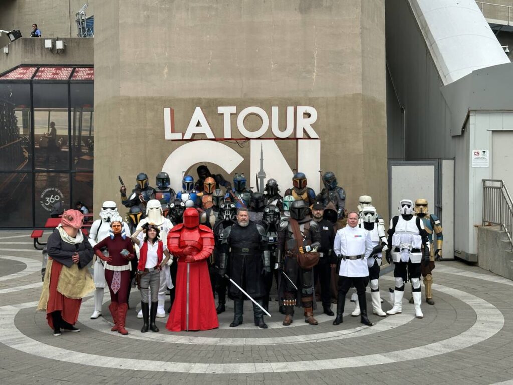 Group of Star Wars cosplayers posing in front of a wall marked “LA TOUR CN,” including stormtrooper-style armour and other character costumes.