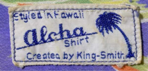 Close-up of a stitched clothing label reading “Etienne A. Hawaii — aloha shirt — Created by King-Smith,” with a small blue palm tree graphic.