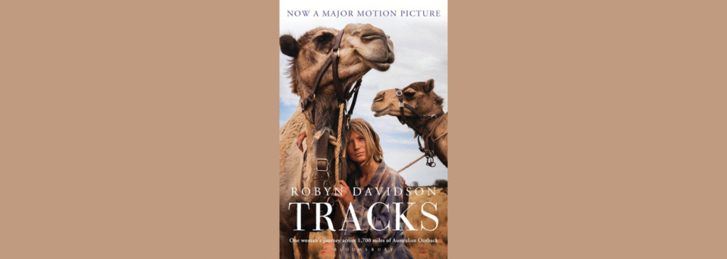 Book cover of Tracks by Robyn Davidson showing a woman standing beside two camels in harness under a wide sky, with the title in large white lettering.