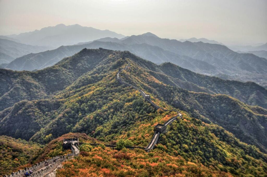 Aerial view of the Great Wall of China winding across green mountain ridges.