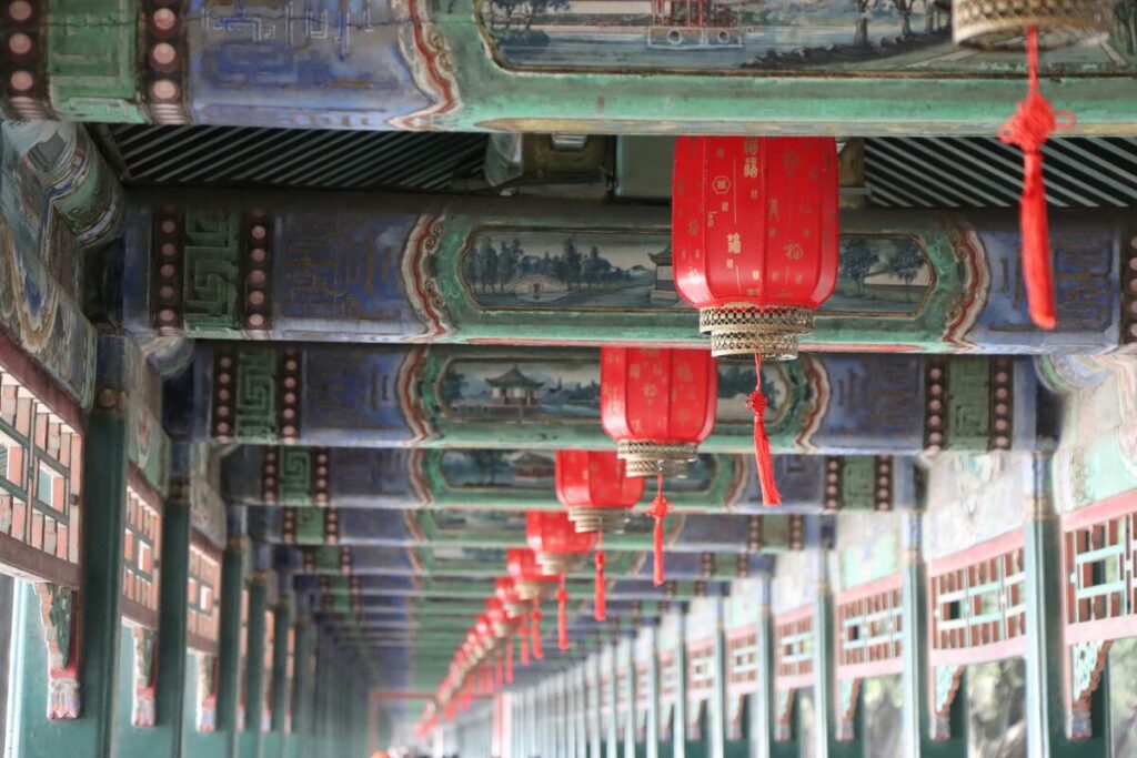 Red lanterns hanging from painted beams inside the Summer Palace in Beijing.