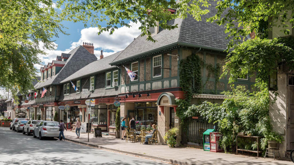 Tree-lined street in the Hydrostone Market district with shops and café patios.