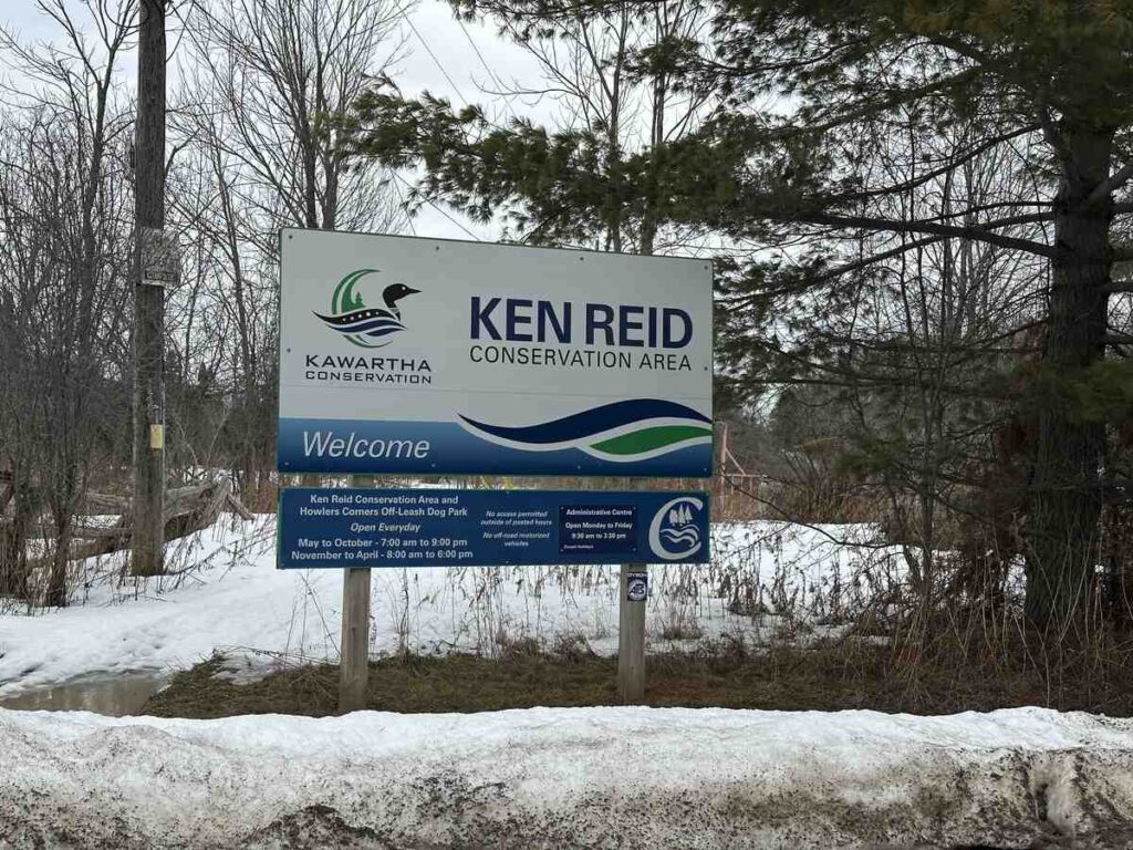 Entrance sign for Ken Reid Conservation Area near Lindsay Ontario surrounded by winter landscape