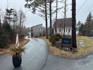 Curving driveway through the Oceanstone property with cottages, trees, and a sign for the main lodge and cottages.