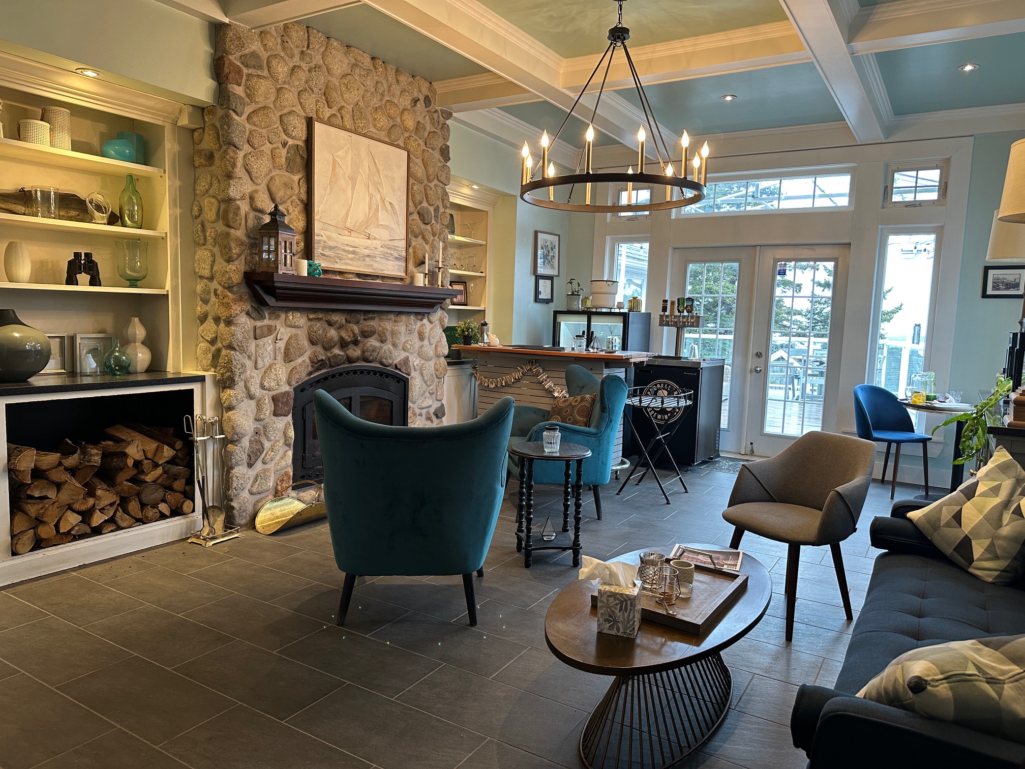 Cozy lounge area beside the check-in desk at Oceanstone Seaside Resort, featuring a stone fireplace, soft seating, and nautical decor.