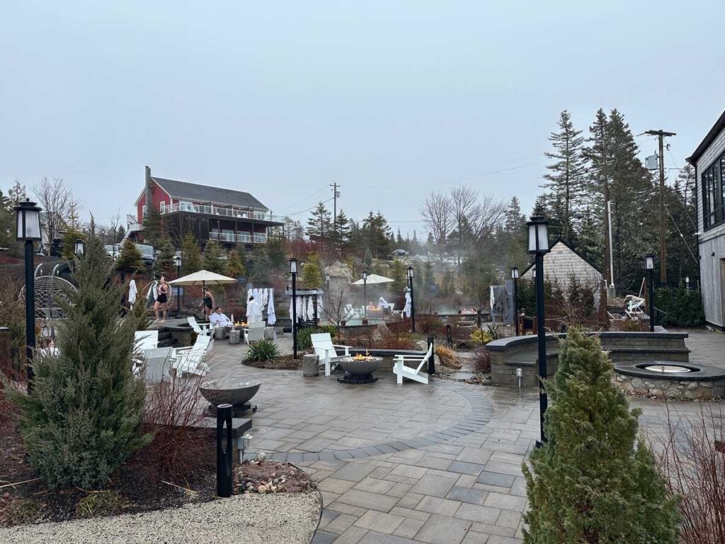 Outdoor hydrothermal spa area at Oceanstone with fire bowls, seating, and pools surrounded by coastal landscaping.