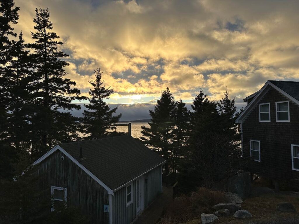 Sunset light breaking through clouds over cottages and trees at Oceanstone Seaside Resort in Nova Scotia.