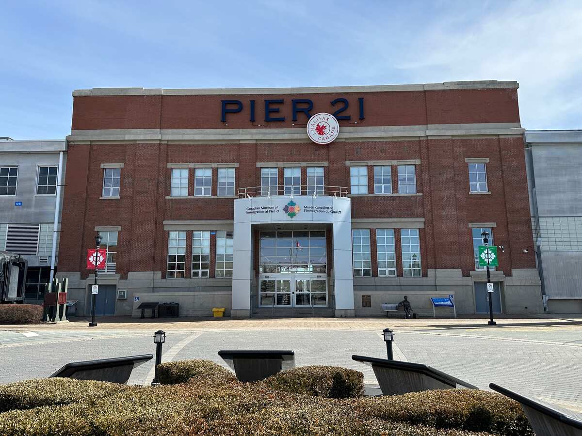 Front exterior of the Canadian Museum of Immigration at Pier 21 in Halifax, a red-brick building with the museum entrance centred below the large “PIER 21” sign.