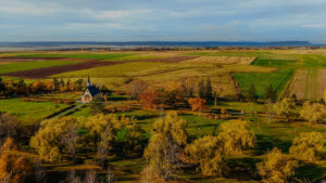 Aerial view of Grand-Pré with the memorial church, formal grounds, and patchwork farmland stretching toward the water.