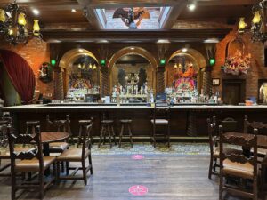 Wooden bar with stools and arched brick backdrop displaying bottles and décor inside Mi Tierra Café