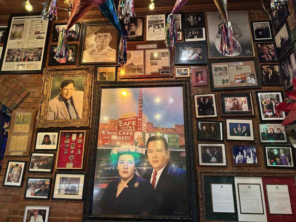 Gallery wall filled with framed photos, certificates, and a central portrait of Mi Tierra’s founders