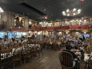 Interior of The Big Texan Steak Ranch in Amarillo, Texas, with Western décor, cow-print tablecloths, and diners seated throughout the restaurant.