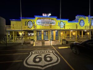 Night exterior of The Big Texan Steak Ranch in Amarillo, Texas, with a Route 66 shield painted in the parking lot.