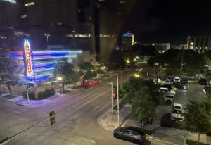 Night view from a hotel room in downtown Amarillo, Texas, showing city streets, parked cars, and the illuminated Amarillo National Bank sign.