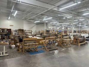 Large weaving studio inside Arts in the Sunset with multiple looms, yarn, textiles, and open workspace.