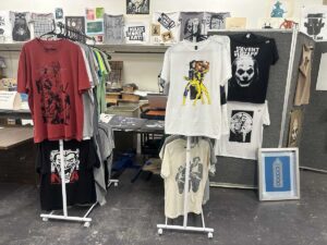Artist-designed T-shirts, prints, and graphic works displayed inside a studio at Arts in the Sunset in Amarillo, Texas.