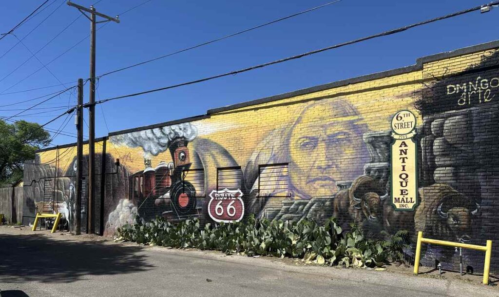 Route 66 mural on the side of 6th Street Antique Mall in Amarillo, Texas, showing a train, Route 66 shield, and historic imagery.