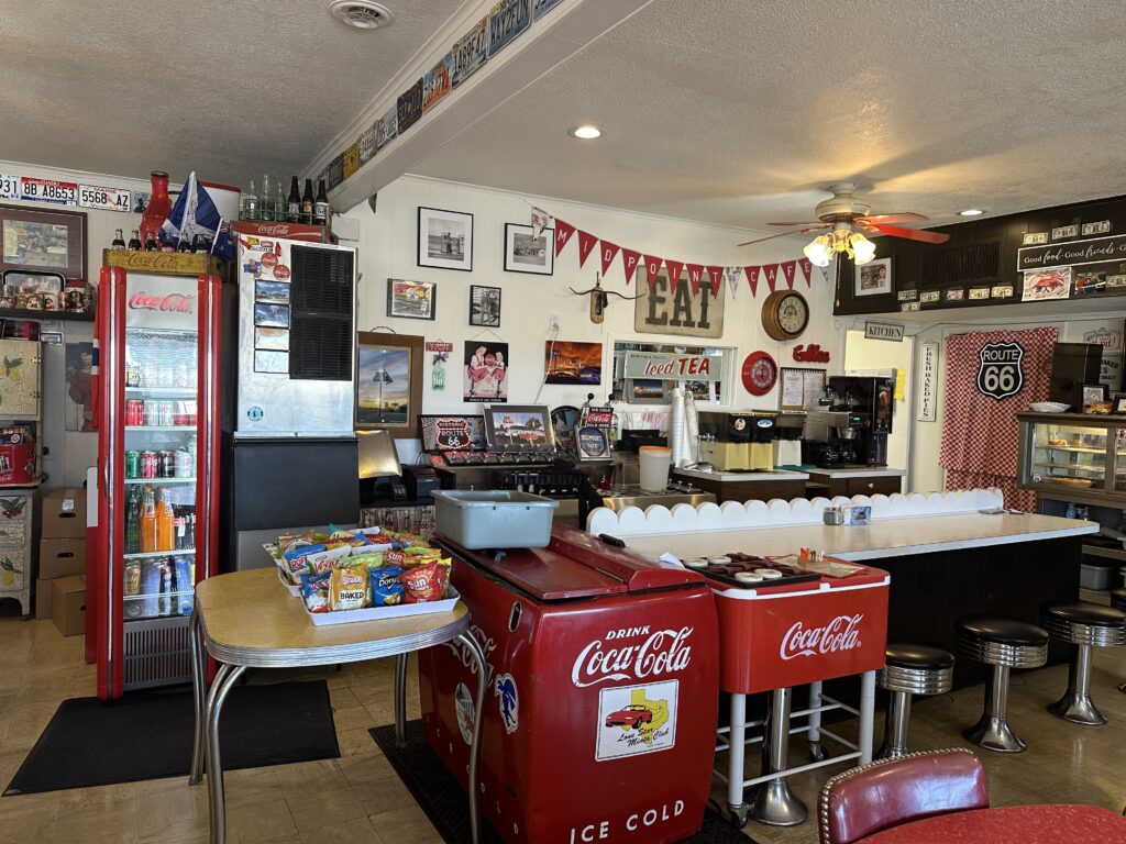 Interior of the Midpoint Café in Adrian, Texas, filled with Route 66 memorabilia, vintage Coca-Cola décor, and diner counter seating.