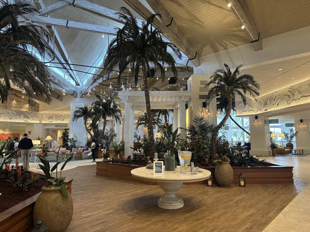 Margaritaville Resort Orlando lobby with indoor palm trees, tropical plants, vaulted wood-beam ceilings, and relaxed seating areas.