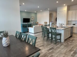 Open-concept cottage interior with dining area, kitchen island, living room, and coastal-inspired decor.
