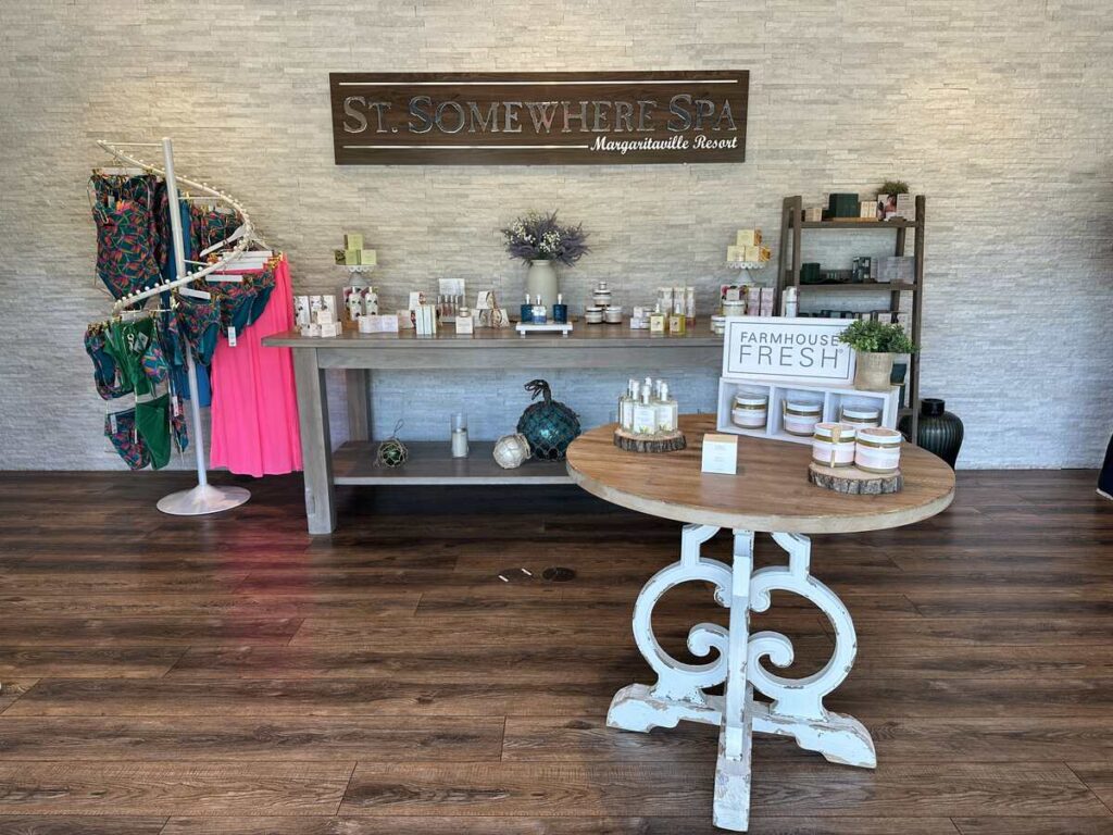 St. Somewhere Spa retail display with skincare products, resort wear, and a wooden spa sign.