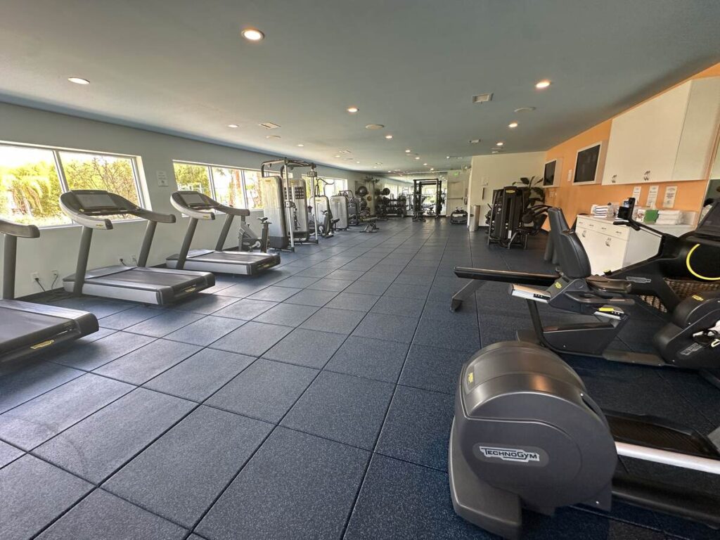 Spacious resort fitness centre with treadmills, cardio machines, weight equipment, and large windows.