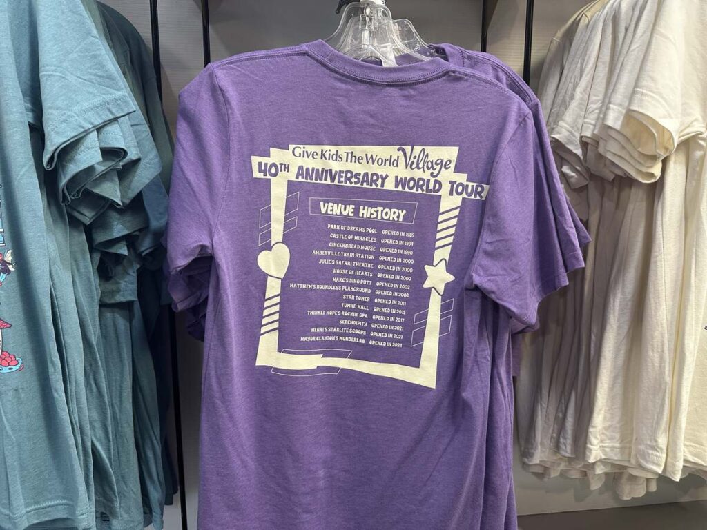Purple Give Kids The World Village anniversary T-shirt displayed in the gift shop.