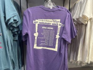 Purple Give Kids The World Village anniversary T-shirt displayed in the gift shop.