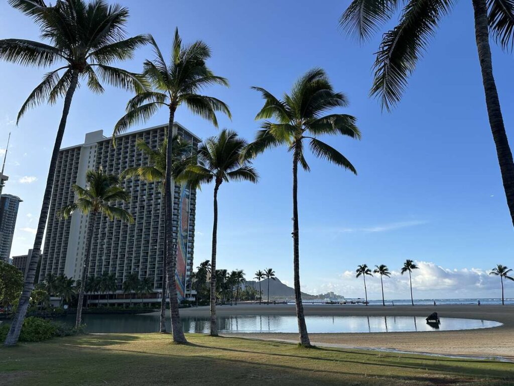 Palm trees, lagoon, beach, and Diamond Head seen from the Waikīkī shoreline.