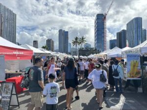 Crowds walking between vendor tents at Kakaʻako Farmers Market in Honolulu.