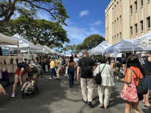 Visitors browsing clothing and artisan stalls at Kakaʻako Farmers Market.