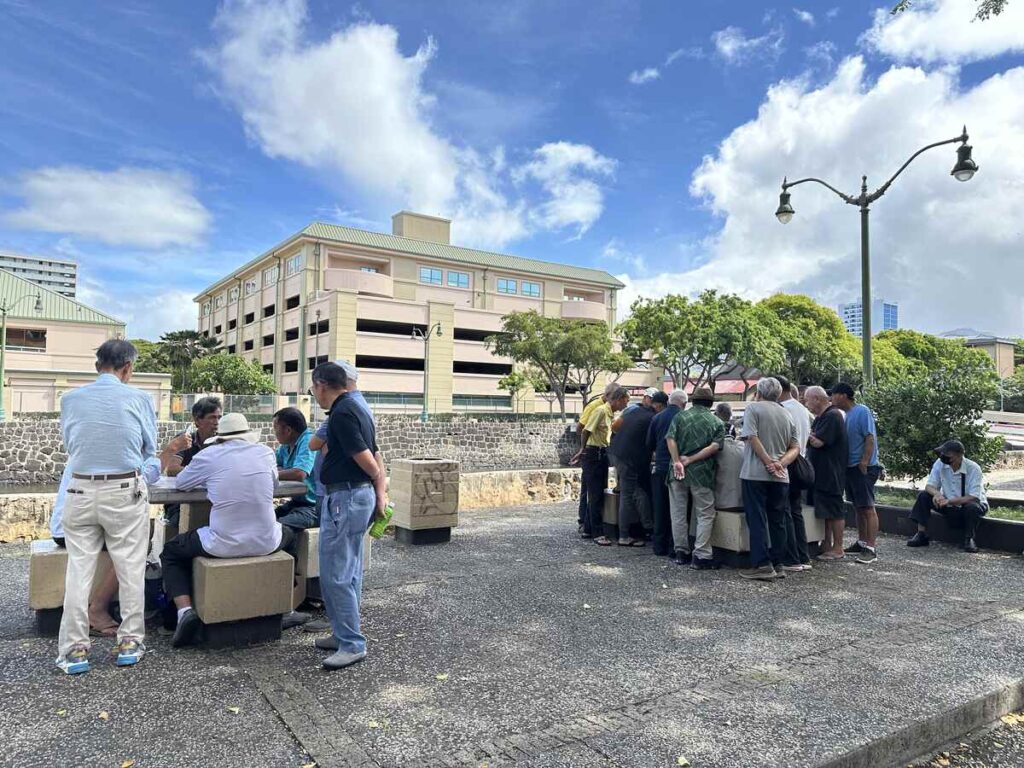 Elderly men gathered outdoors playing games in Honolulu’s Chinatown.