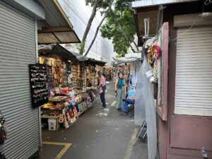 Vendor stalls lining a narrow walkway at Duke’s Marketplace in Waikīkī.