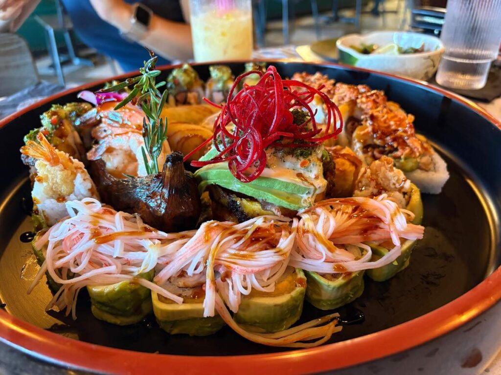 Large platter of colourful sushi rolls with avocado, shrimp, crab, sauces, and garnishes at Daddy Ninja in Kissimmee.