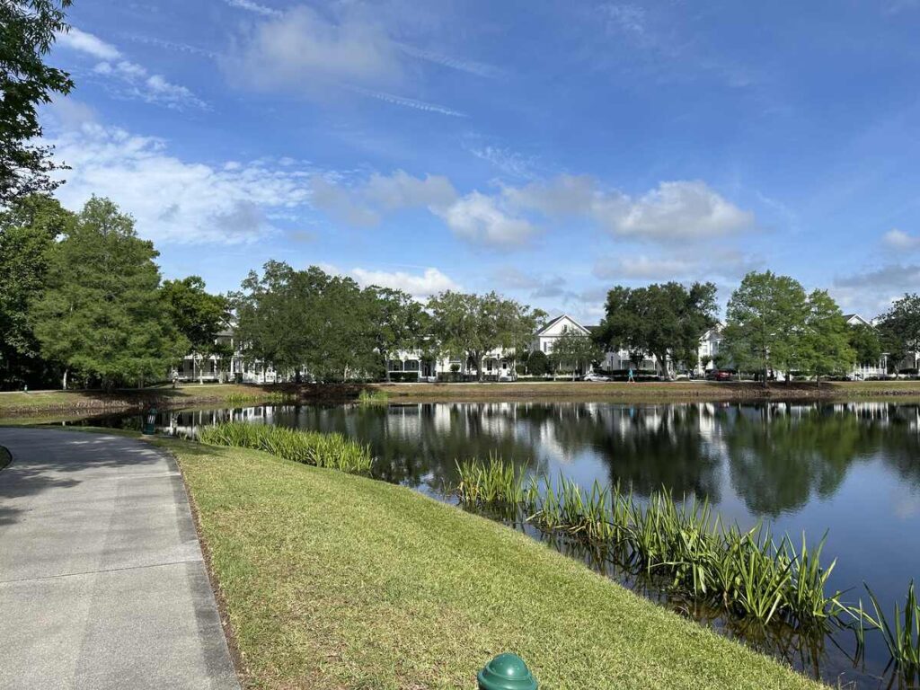Curving paved path beside a calm lake in Celebration, Florida, with white homes reflected in the water.