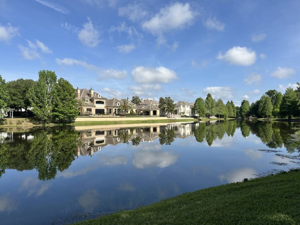 Large homes, trees, and clouds reflected in a calm lake in Celebration, Florida.