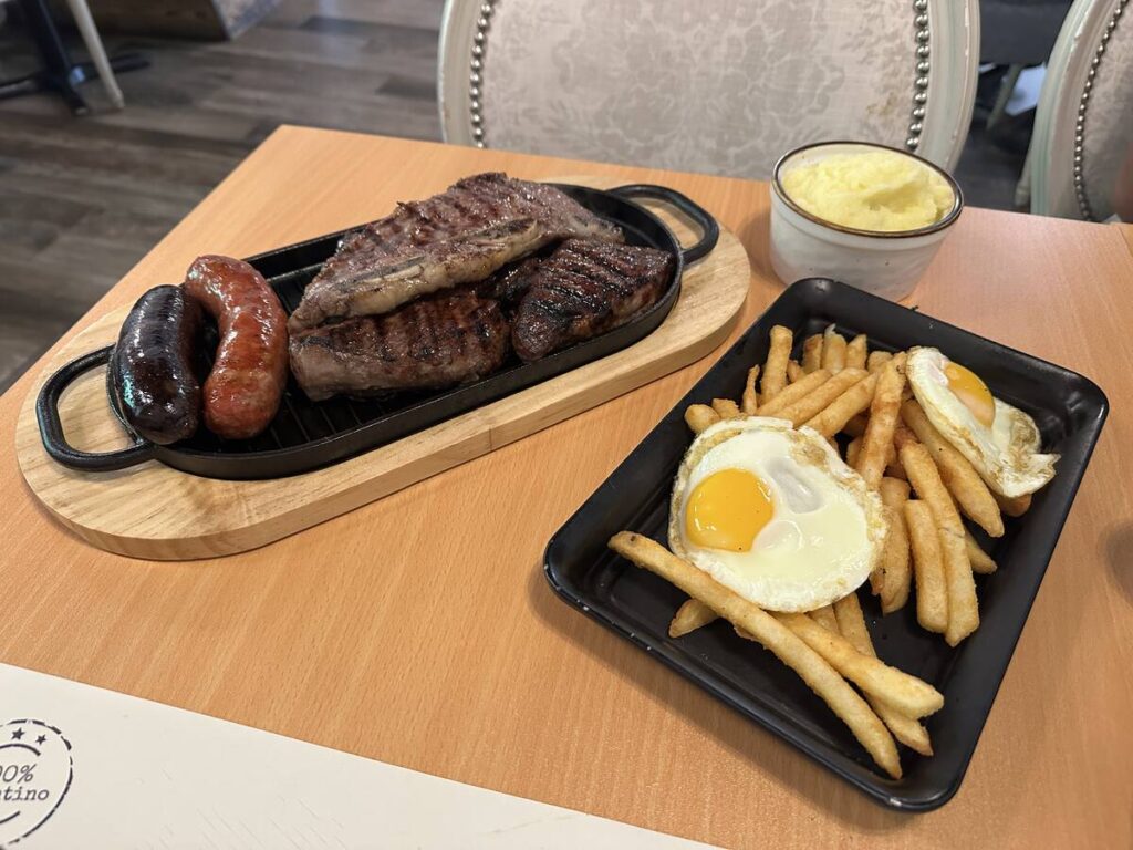 Argentinian mixed grill with steak, sausages, fries, fried eggs, and mashed potatoes at Alma Argentina in Kissimmee.