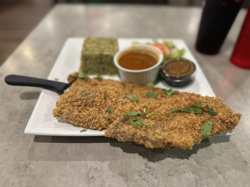 Breaded cutlet served with green rice, sauce, and salad at a Latin restaurant in Kissimmee.