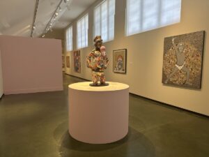 A contemporary art gallery at the Honolulu Museum of Art with colourful paintings and a sculptural figure on display.