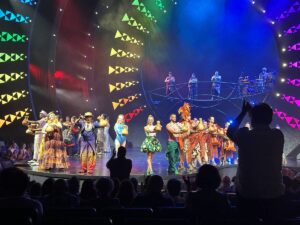 Performers take the stage during Cirque du Soleil’s ʻAuana in Waikīkī, surrounded by colourful lights and musicians.
